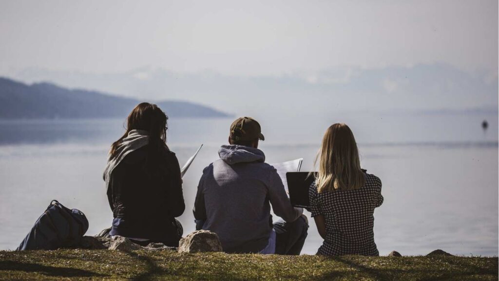 Drei Schüler der FOS Starnberg sitzen am Starnberger See und lernen